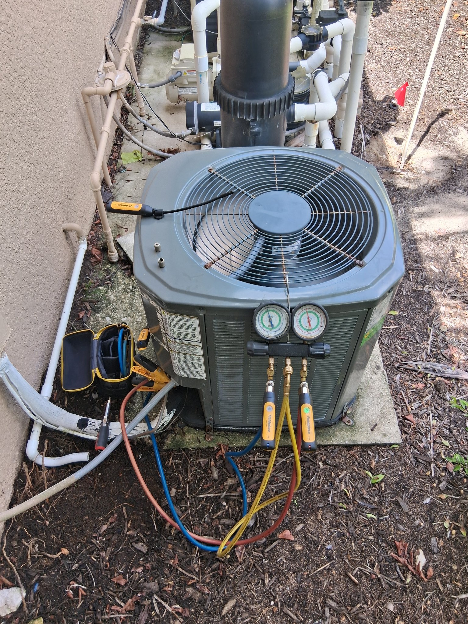 Corbett Cooling technician servicing a condenser with manifold gauges
